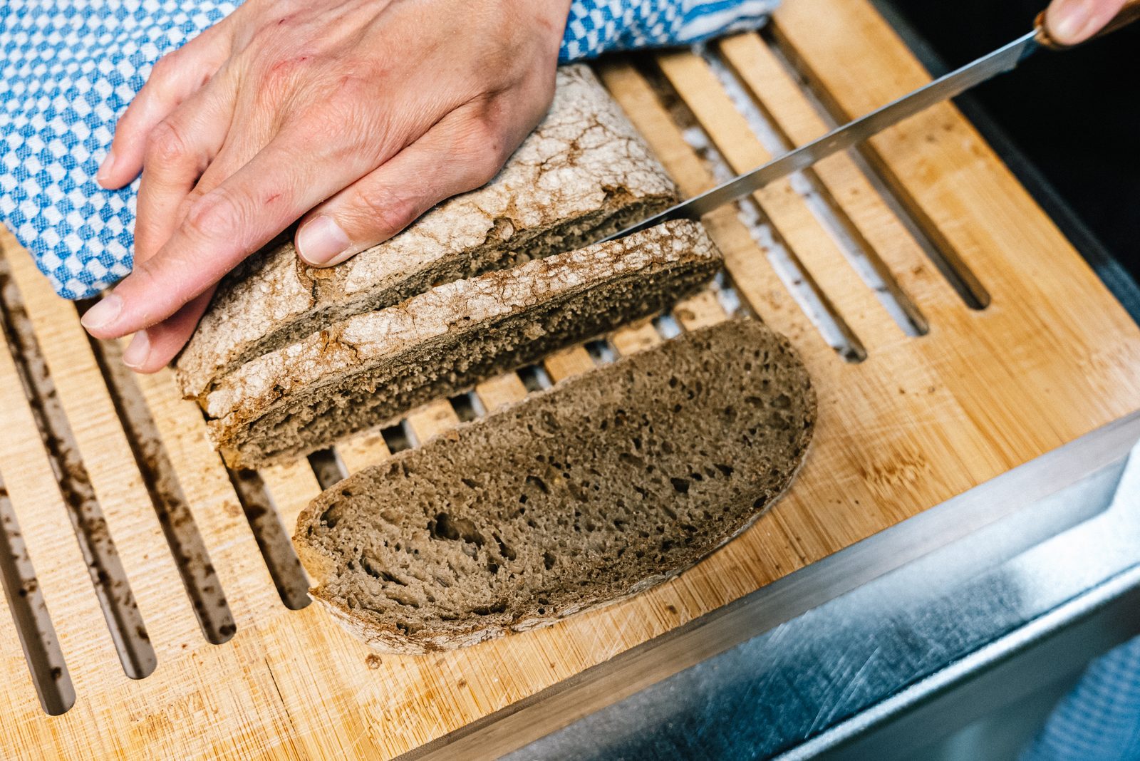 Fresh sourdough bread being sliced by hand.